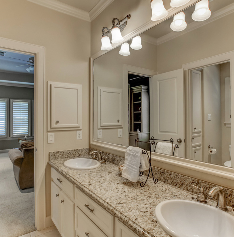 bathroom with natural light, his and hers vanity, and mirror