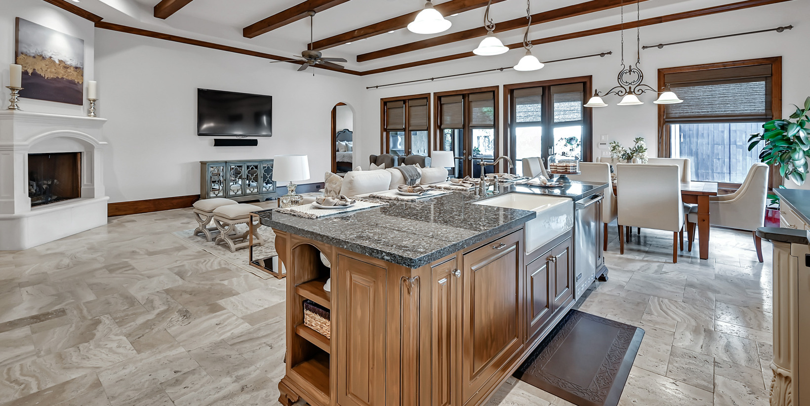 kitchen featuring natural light, a fireplace, a center island, TV, light flooring, granite-like countertops, pendant lighting, and brown cabinetry
