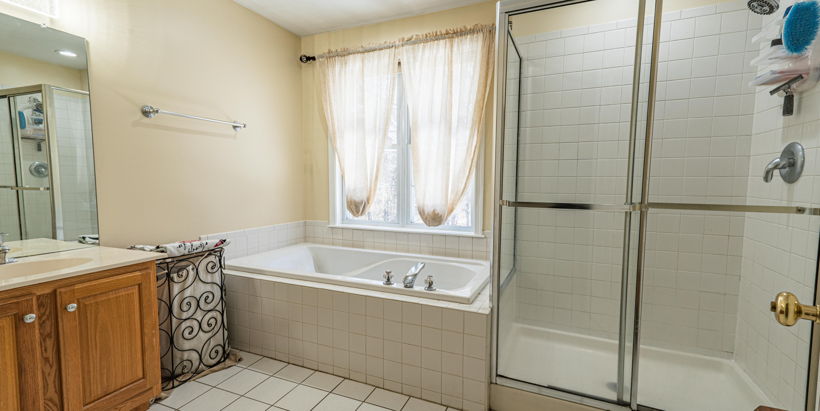 bathroom with natural light, tile flooring, vanity with extensive cabinet space, separate shower and tub enclosures, and mirror
