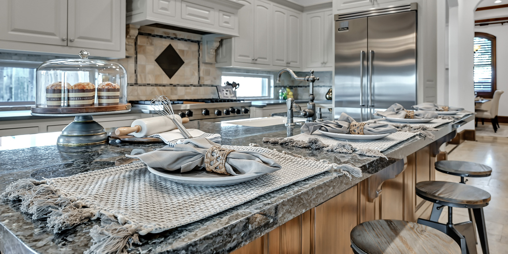 kitchen featuring a wealth of natural light, refrigerator, gas stovetop, ventilation hood, pendant lighting, and dark stone countertops