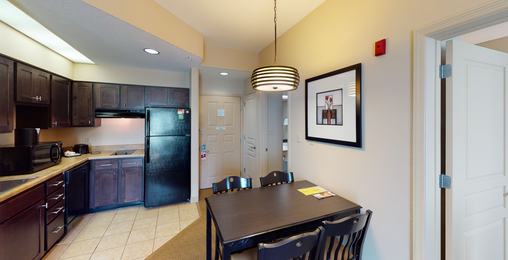 kitchen with refrigerator, light tile floors, and dark brown cabinets