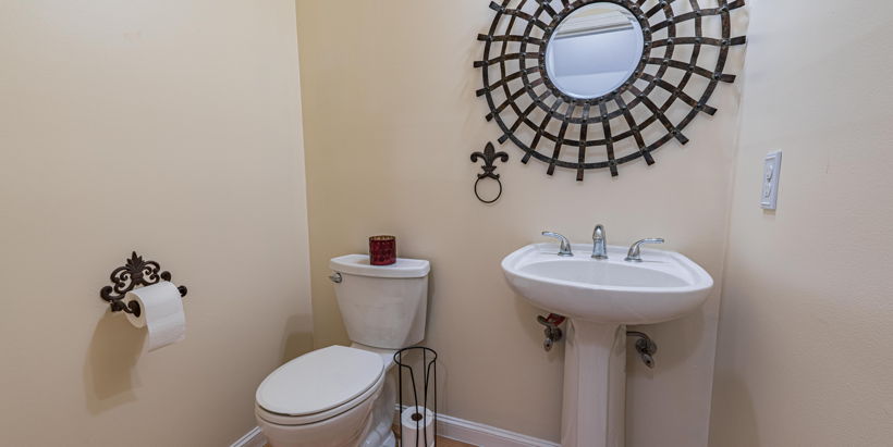 half bath featuring hardwood flooring, washbasin, toilet, and mirror