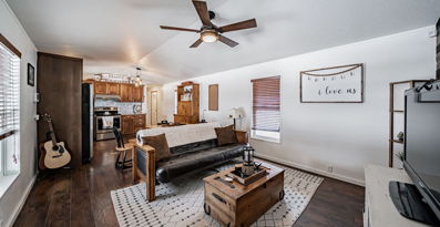 hardwood floored living room with a ceiling fan, natural light, and TV